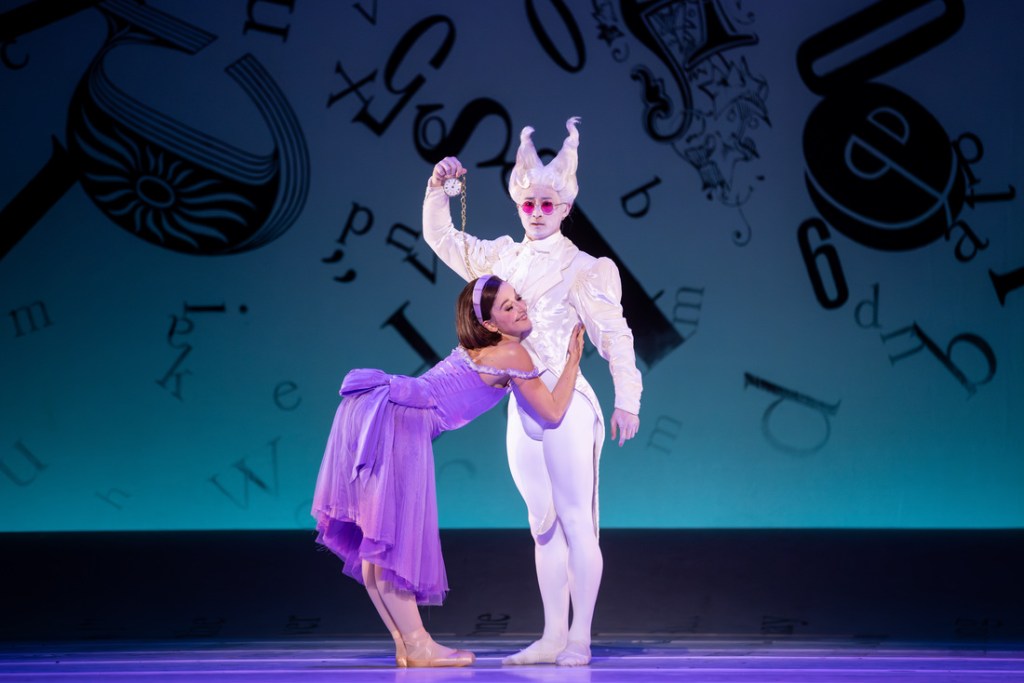 Benedicte Bemet as Alice and Chengwu Guo as the White Rabbit in The Australian Ballet's 2024 production of Alice's Adventures in Wonderland. Captured mid-performance, Bemet portrays Alice's curiosity and wonder, while Guo embodies the urgency of the White Rabbit, both adorned in vibrant, whimsical costumes that reflect the fantastical world of Wonderland.