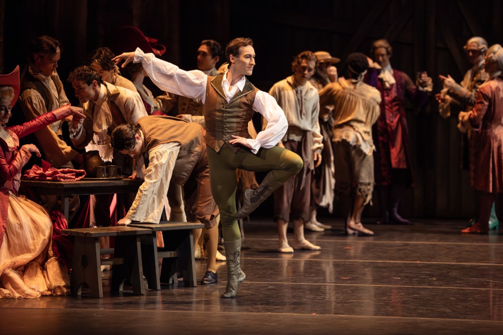 Brett Chynoweth as Lescaut in the 2025 production of Manon by The Australian Ballet. Captured in a dramatic moment on stage, Chynoweth's portrayal of the morally ambiguous character is highlighted by intense lighting and period-appropriate costume, reflecting the character's complex role in the narrative.
