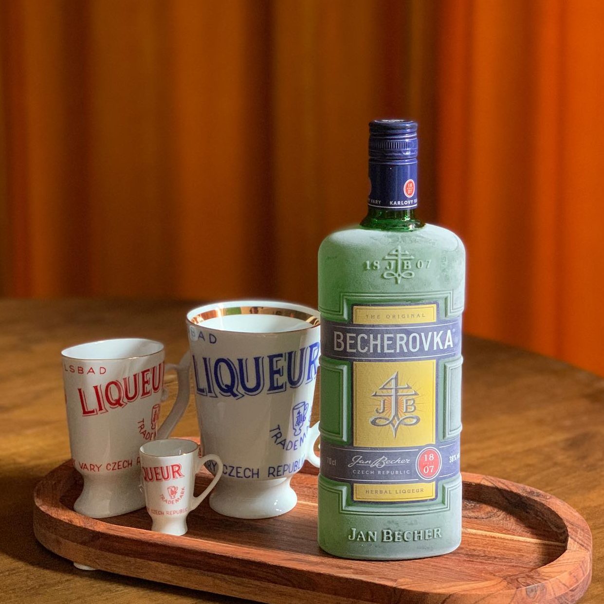 A serving plate with empty tea cups and a frosted bottle of Becherovka, a herbal Czech liqueur.